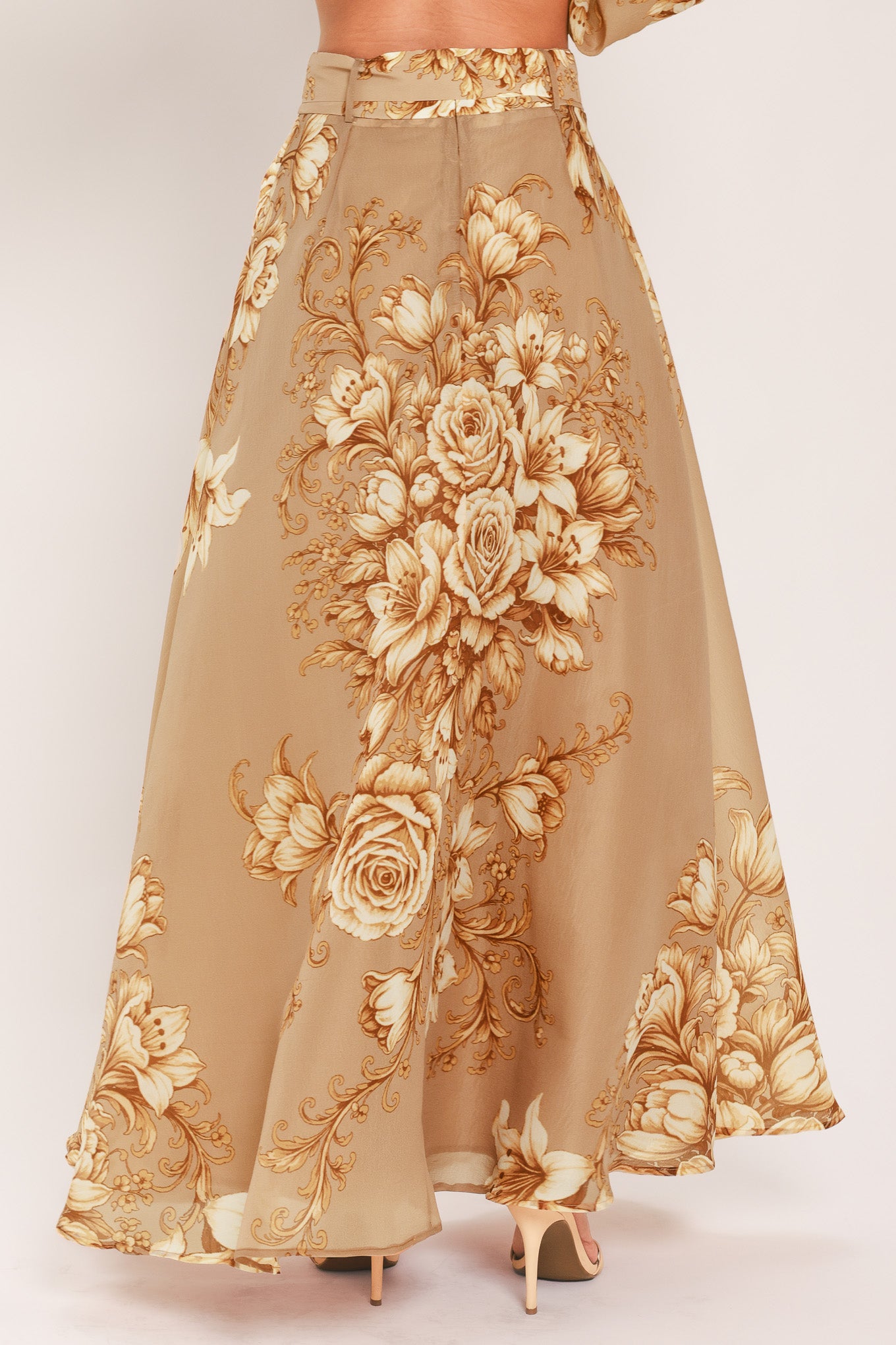 A floor-length beige skirt with a large gold and cream floral rose pattern, featuring a matching beaded belt, shown on a model | Flying Tomato