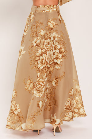 A floor-length beige skirt with a large gold and cream floral rose pattern, featuring a matching beaded belt, shown on a model | Flying Tomato