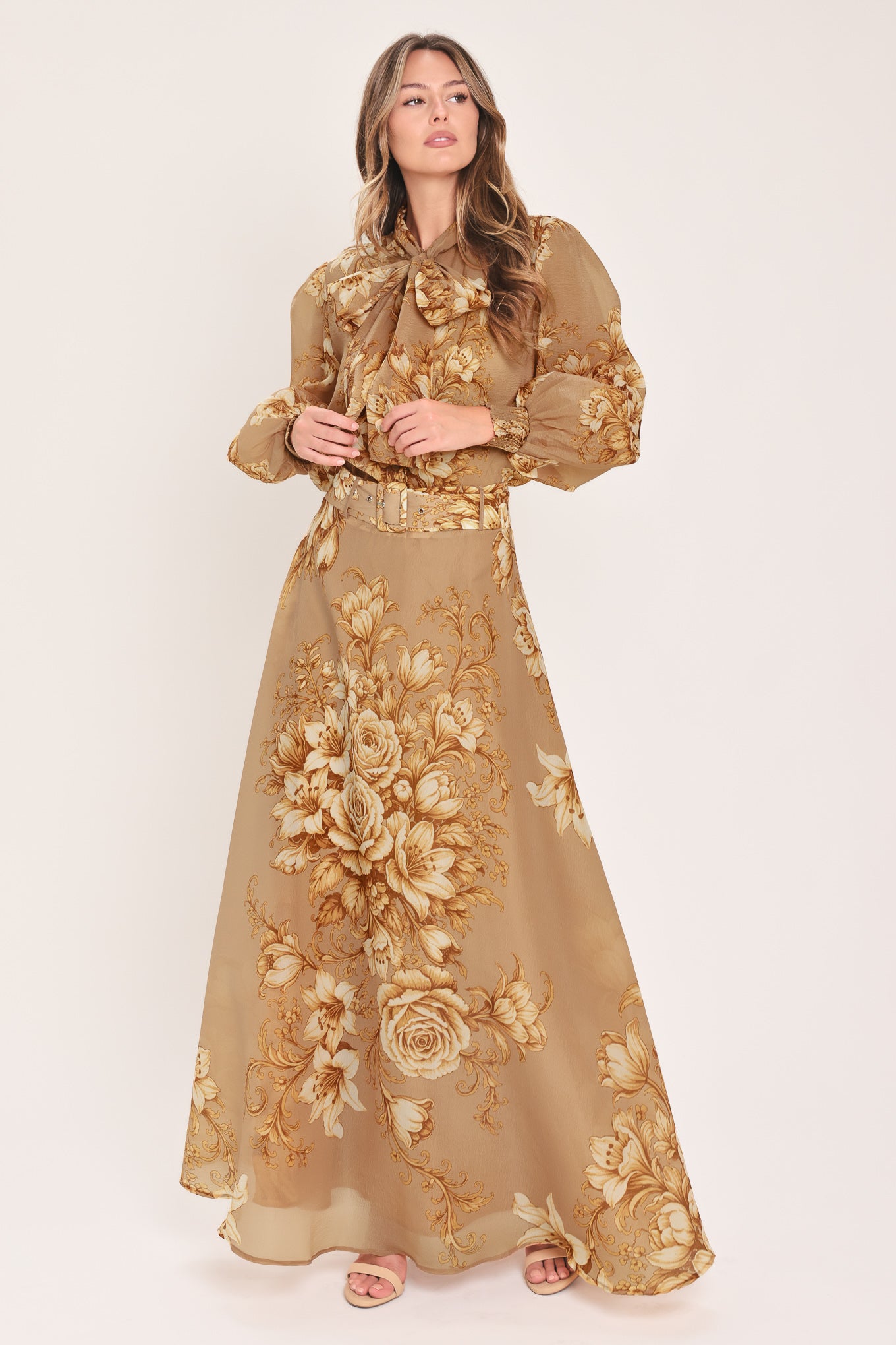 A floor-length beige skirt with a large gold and cream floral rose pattern, featuring a matching beaded belt, shown on a model | Flying Tomato