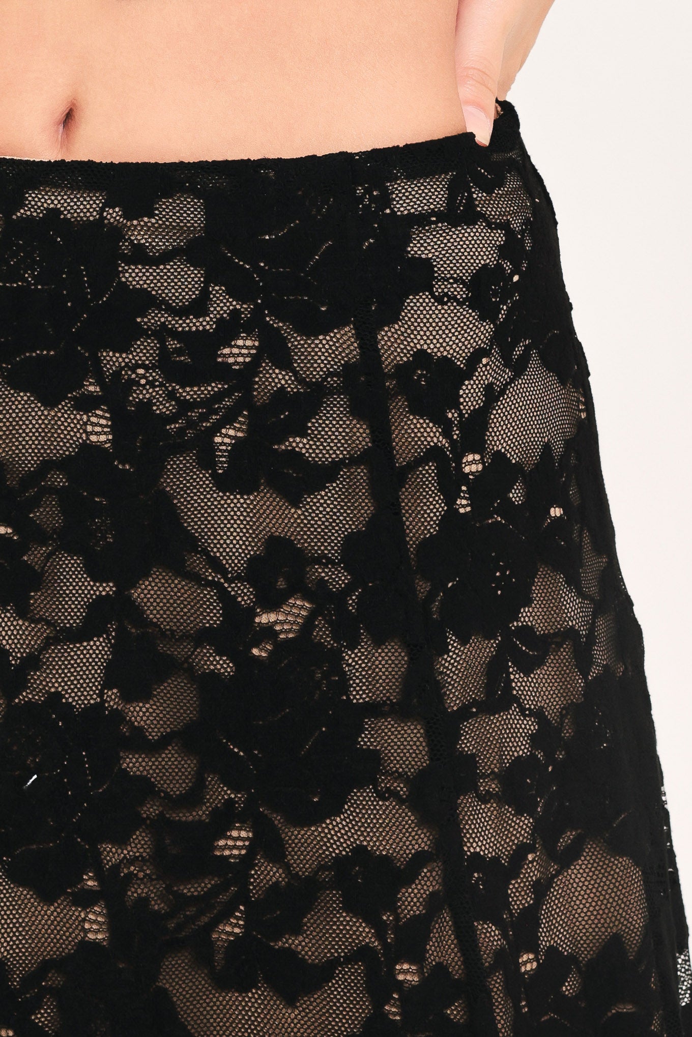 Woman wearing a long black lace skirt with a nude base | Flying Tomato