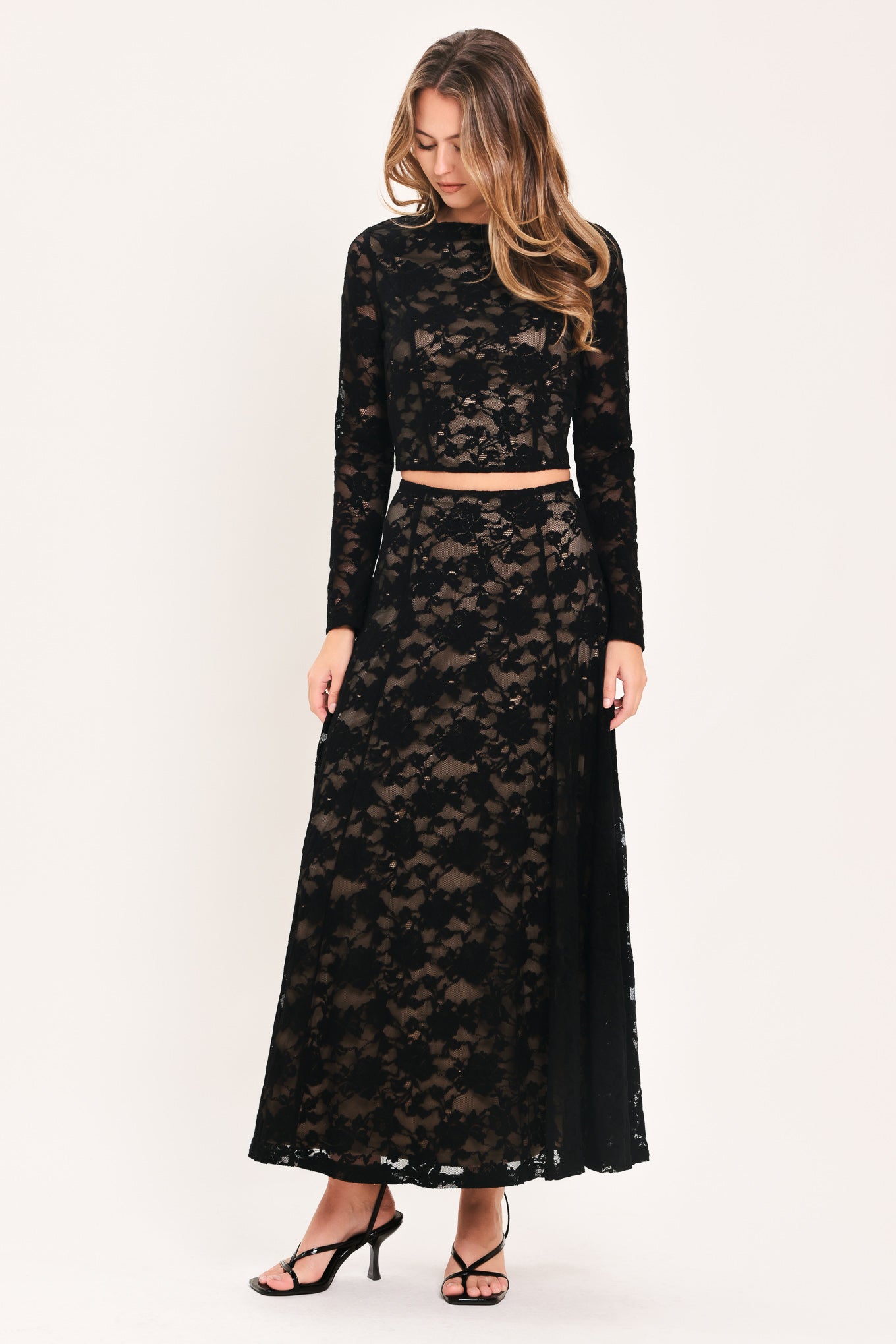 Woman wearing a long black lace skirt with a nude base | Flying Tomato