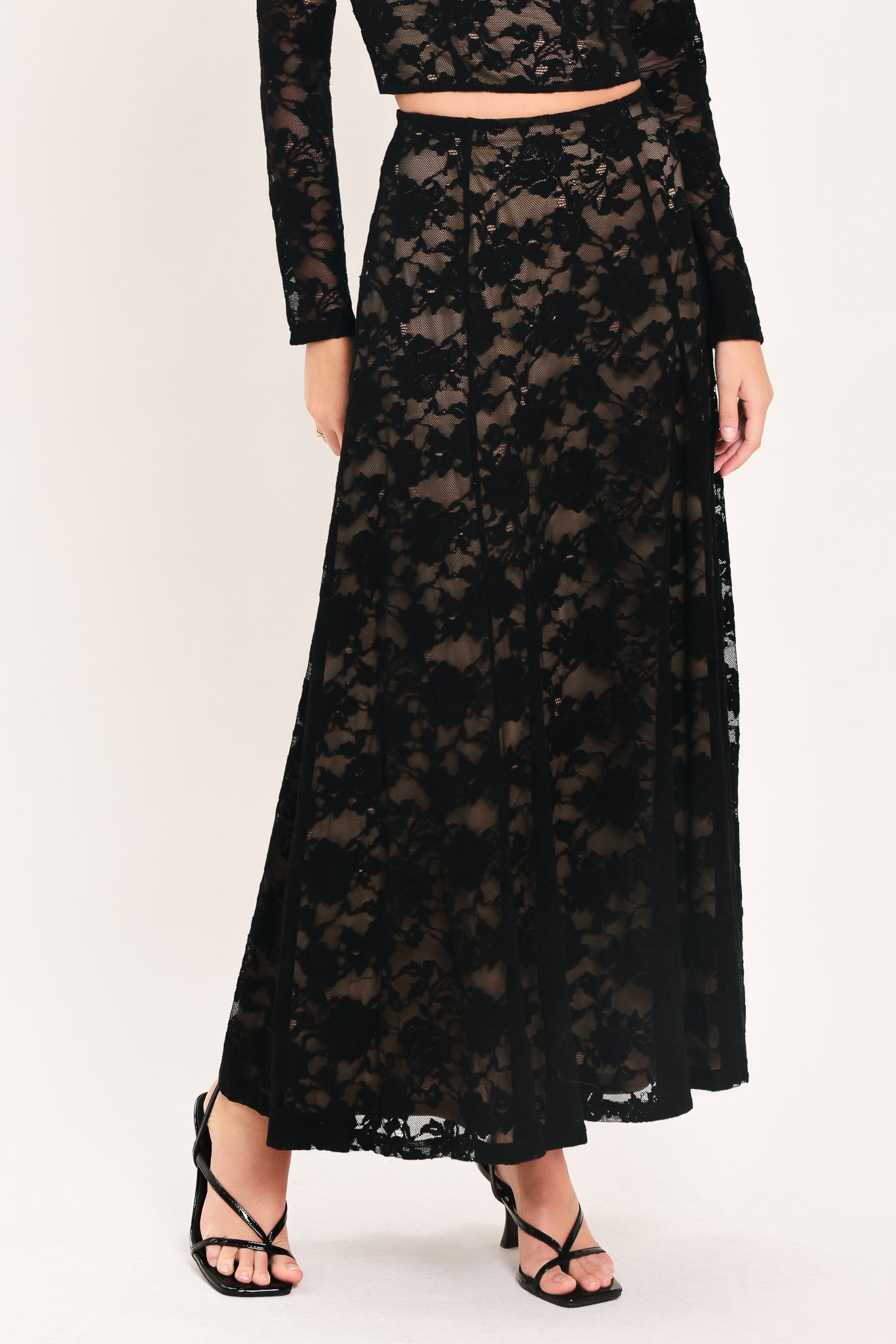 Woman wearing a long black lace skirt with a nude base | Flying Tomato