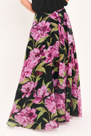 A black maxi skirt with a large pink floral print and green leaves, shown on a model | Flying Tomato