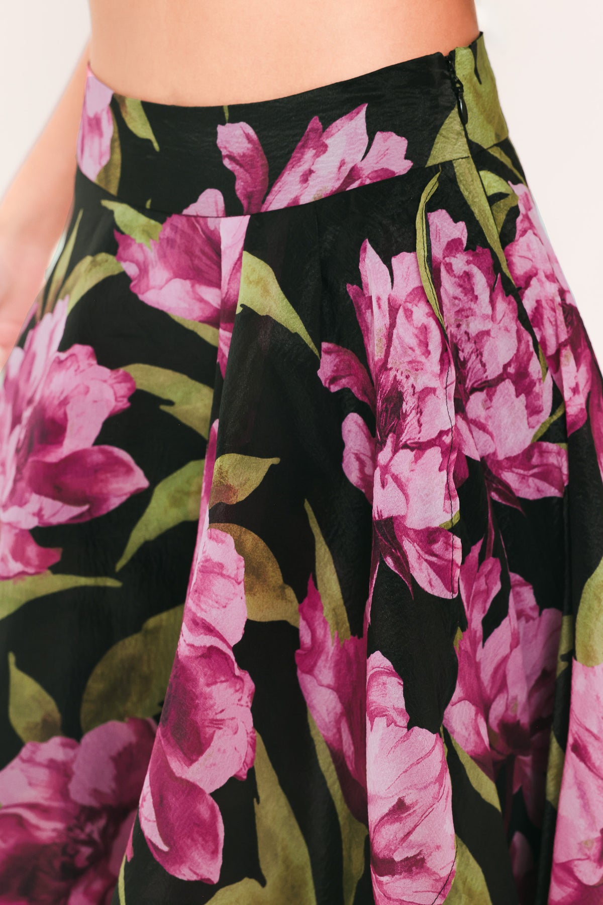 A black maxi skirt with a large pink floral print and green leaves, shown on a model | Flying Tomato