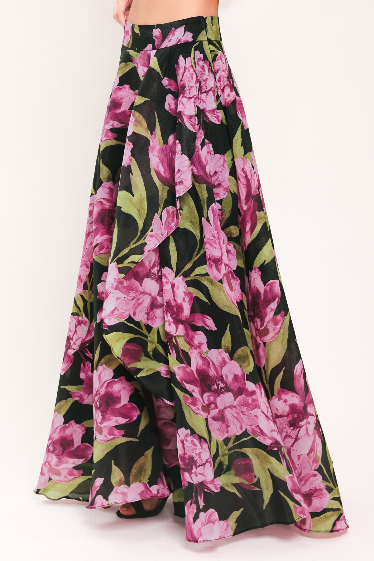 A black maxi skirt with a large pink floral print and green leaves, shown on a model | Flying Tomato