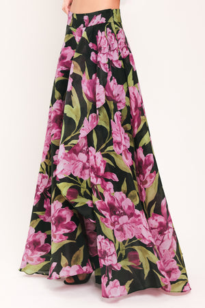 A black maxi skirt with a large pink floral print and green leaves, shown on a model | Flying Tomato