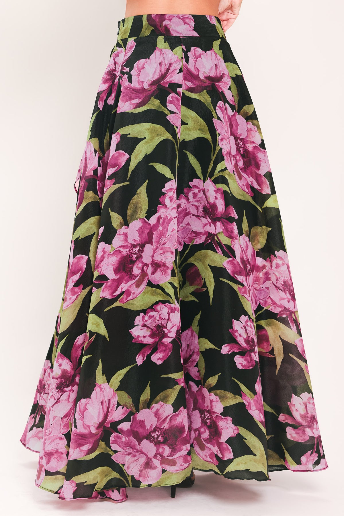 A black maxi skirt with a large pink floral print and green leaves, shown on a model | Flying Tomato