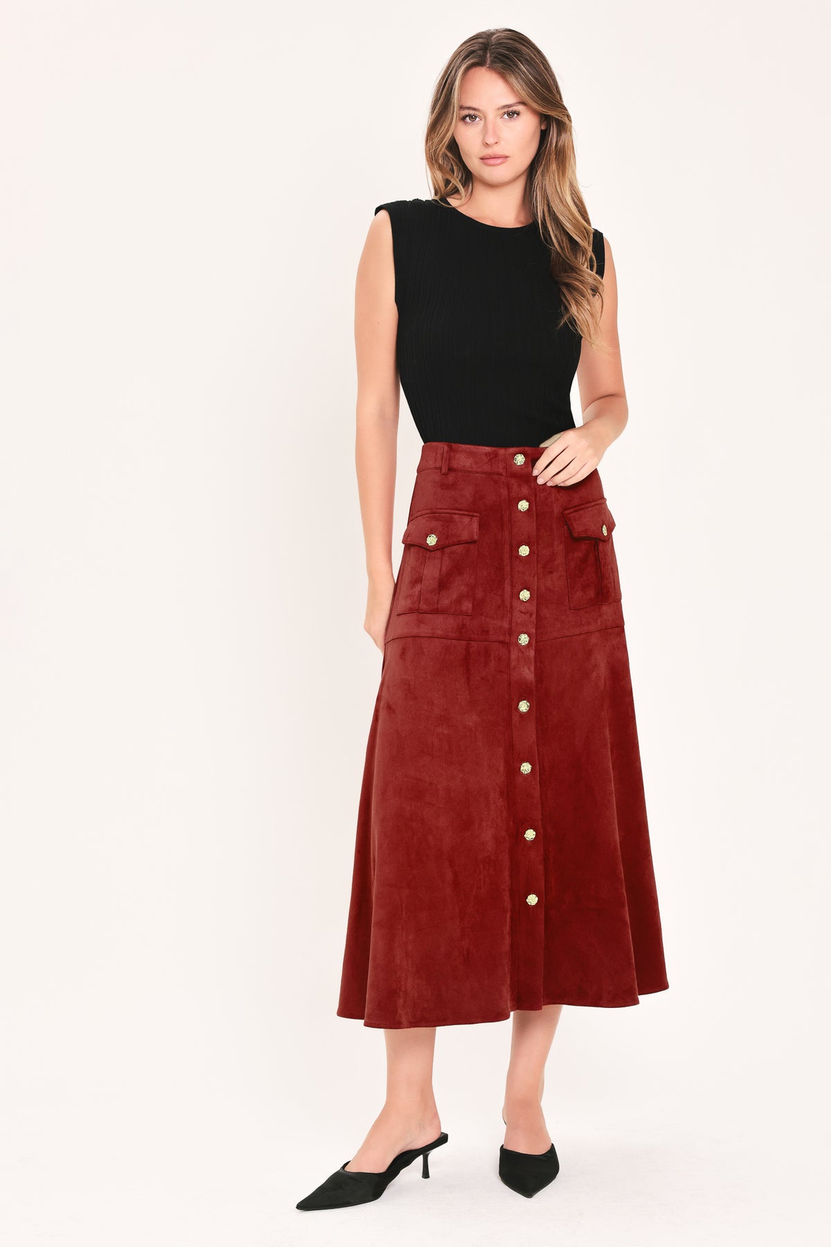 A brick colored suede midi skirt with a button-down front, flap pockets, and gold-tone button accents, shown on a model | Flying Tomato