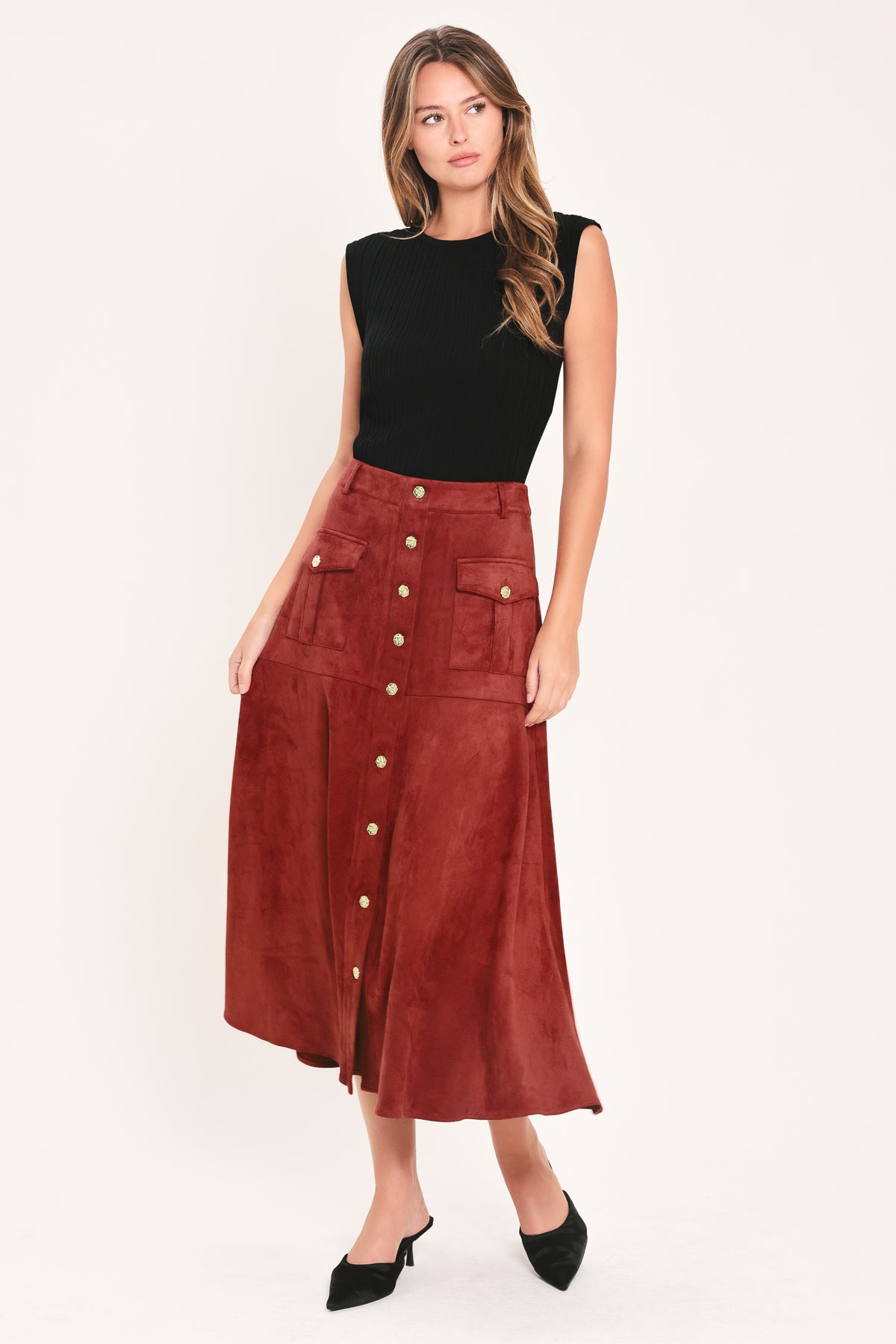 A brick colored suede midi skirt with a button-down front, flap pockets, and gold-tone button accents, shown on a model | Flying Tomato