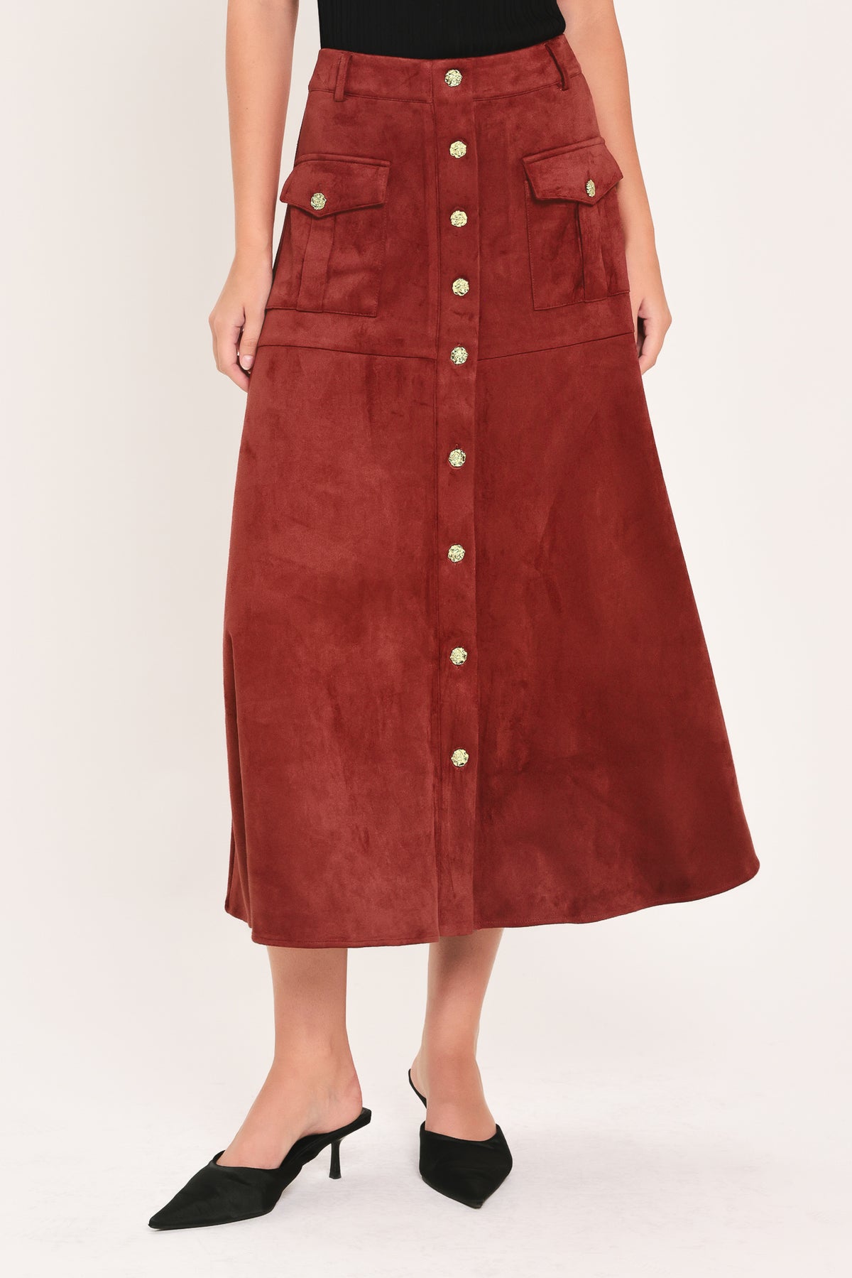 A brick colored suede midi skirt with a button-down front, flap pockets, and gold-tone button accents, shown on a model | Flying Tomato