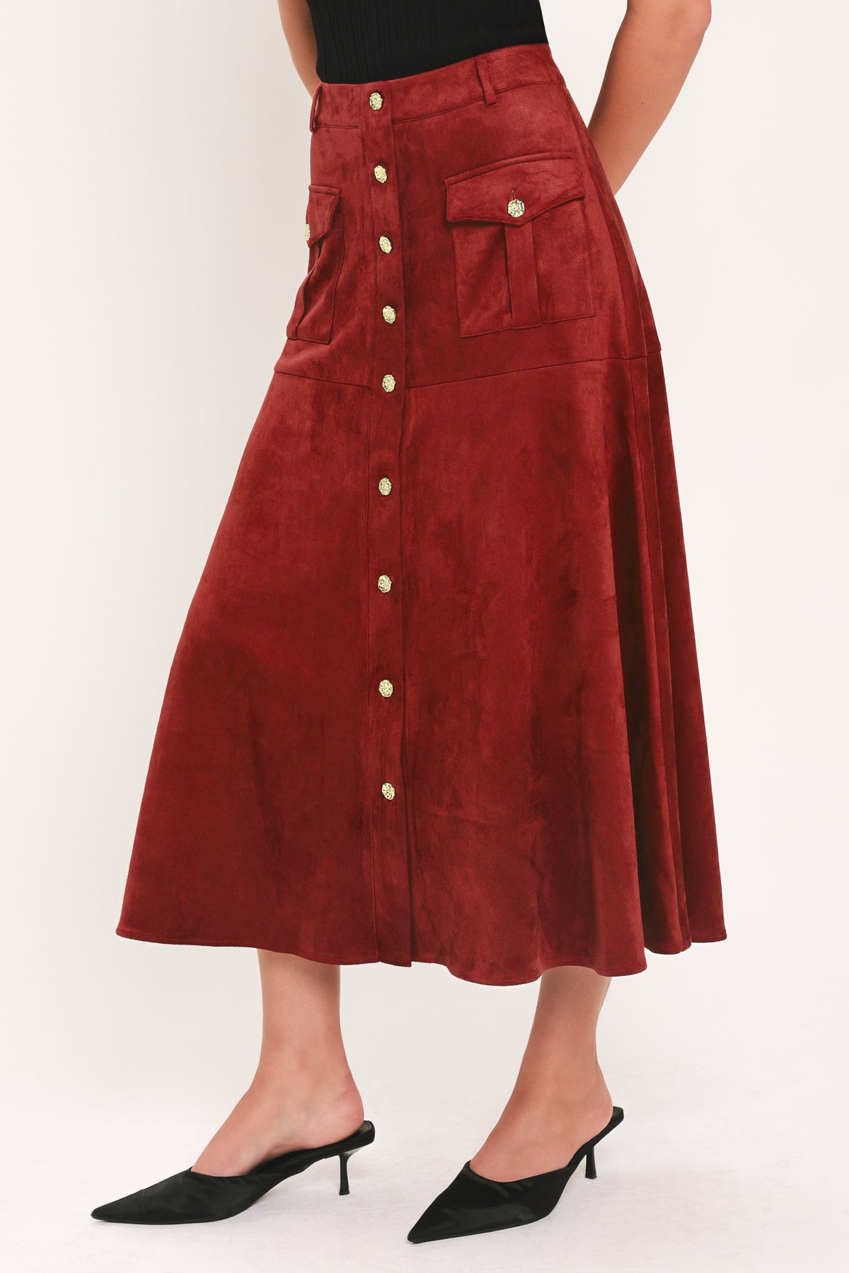 A brick colored suede midi skirt with a button-down front, flap pockets, and gold-tone button accents, shown on a model | Flying Tomato