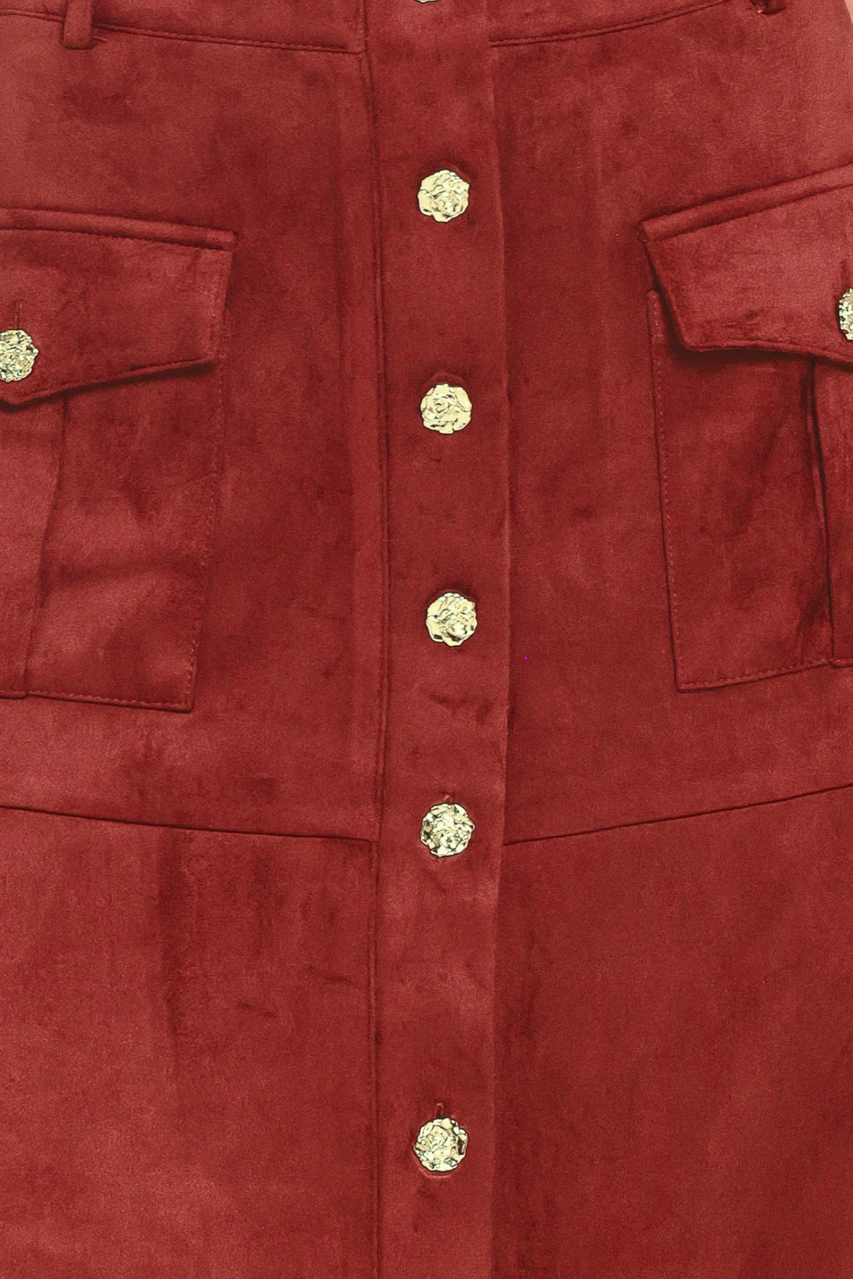 A brick colored suede midi skirt with a button-down front, flap pockets, and gold-tone button accents, shown on a model | Flying Tomato
