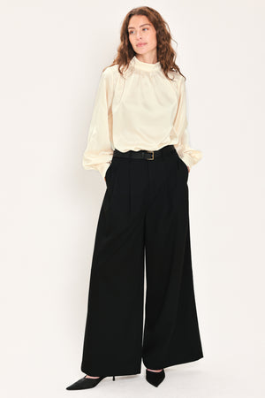 Woman wearing high-waisted, wide-leg trousers with pleats and coordinating belt | Flying Tomato
