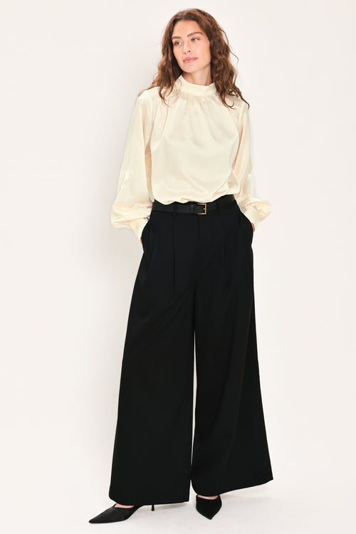 Woman wearing high-waisted, wide-leg trousers with pleats and coordinating belt | Flying Tomato