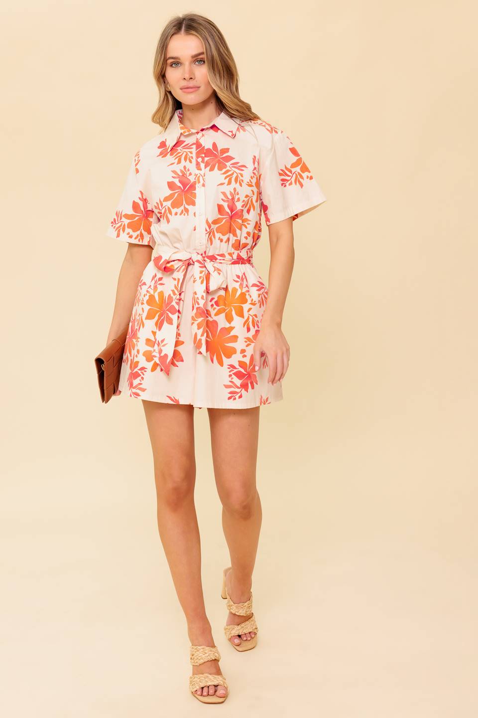 A printed woven romper featuring collar, button down, short sleeve, self sash tie and elasticized waist