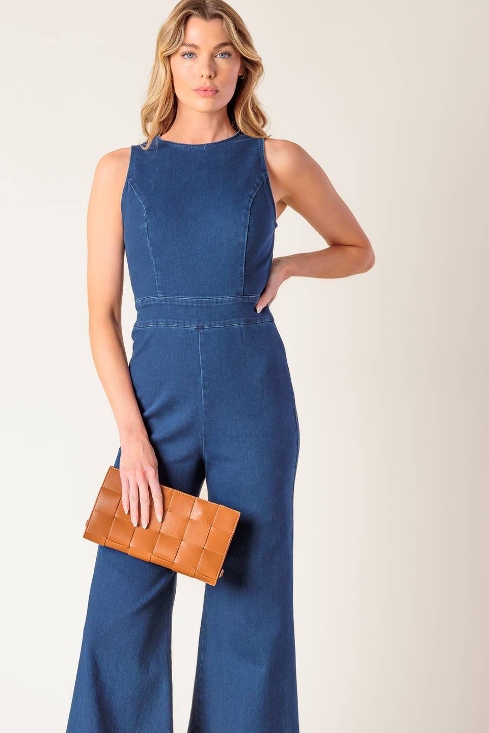 A washed stretch denim jumpsuit featuring round neckline, sleeveless, wide leg and bare back with heart shape cut out and zipper closure.