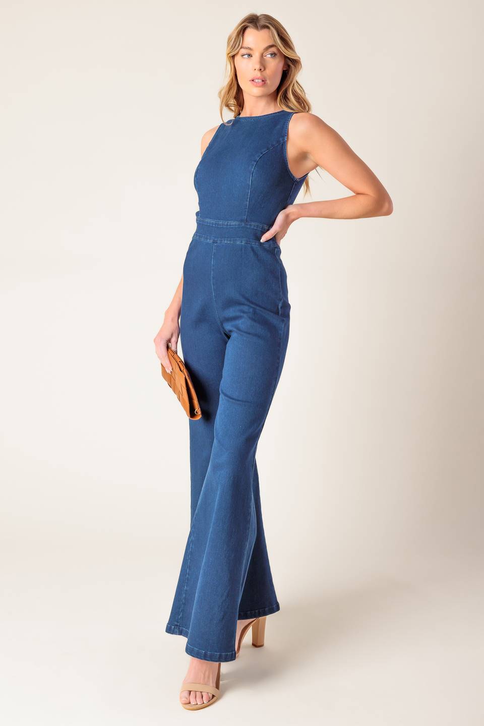 A washed stretch denim jumpsuit featuring round neckline, sleeveless, wide leg and bare back with heart shape cut out and zipper closure.