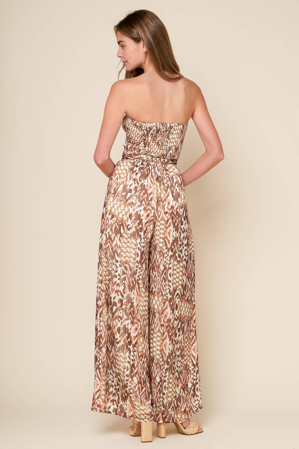 
A printed woven jumpsuit with a strapless, smocked bodice, self sash, and wide leg, perfect for a VACAY