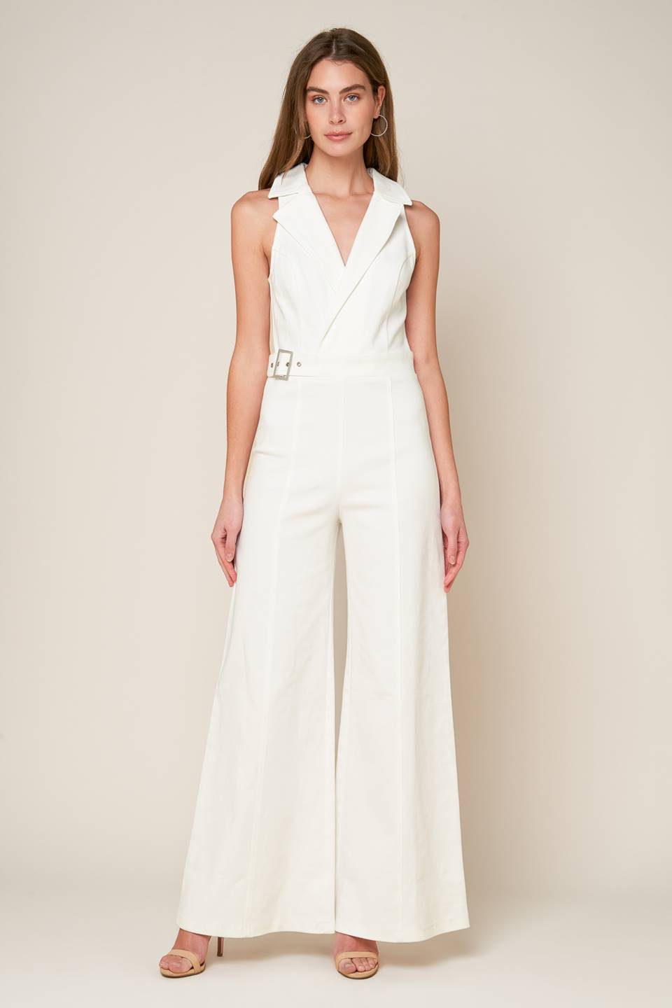 A sleeveless solid white woven jumpsuit featuring surplice neckline with collar, attached side belt, wide leg and back zipper closure.