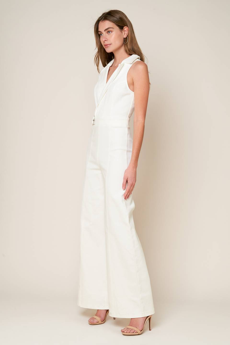 A sleeveless solid white woven jumpsuit featuring surplice neckline with collar, attached side belt, wide leg and back zipper closure.