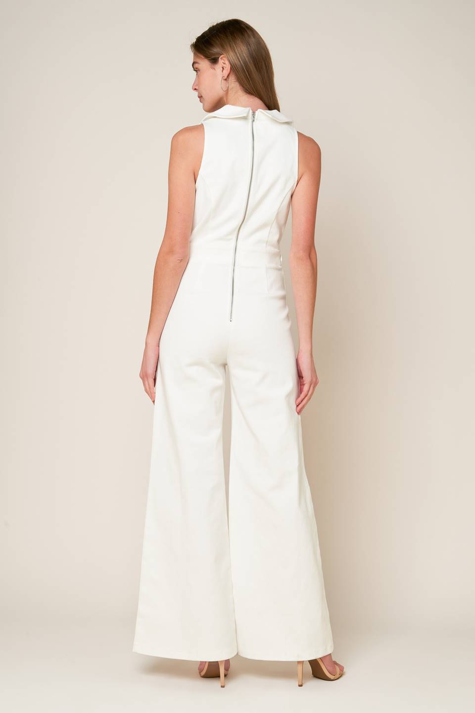 A sleeveless solid white woven jumpsuit featuring surplice neckline with collar, attached side belt, wide leg and back zipper closure.