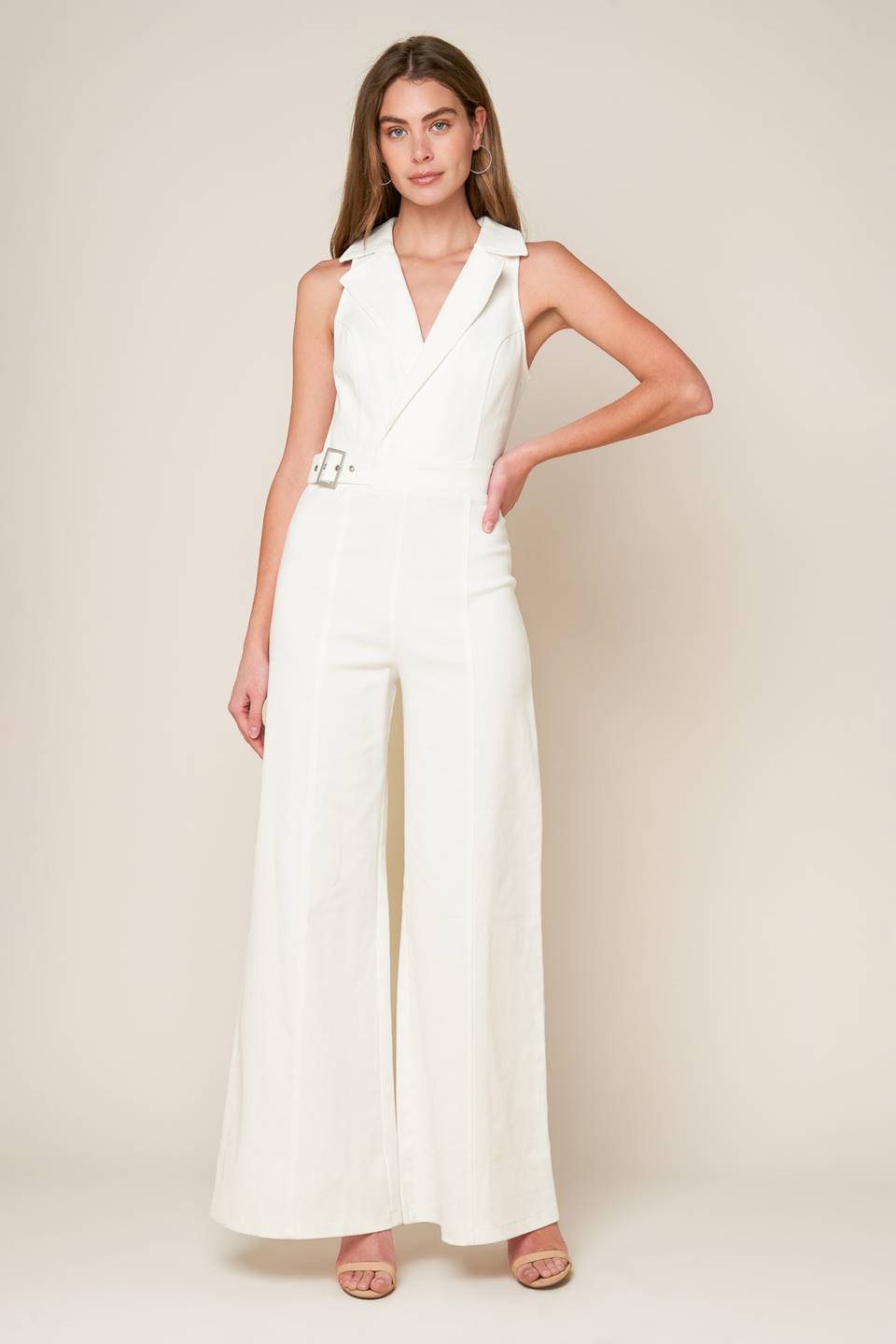 A sleeveless solid white woven jumpsuit featuring surplice neckline with collar, attached side belt, wide leg and back zipper closure.