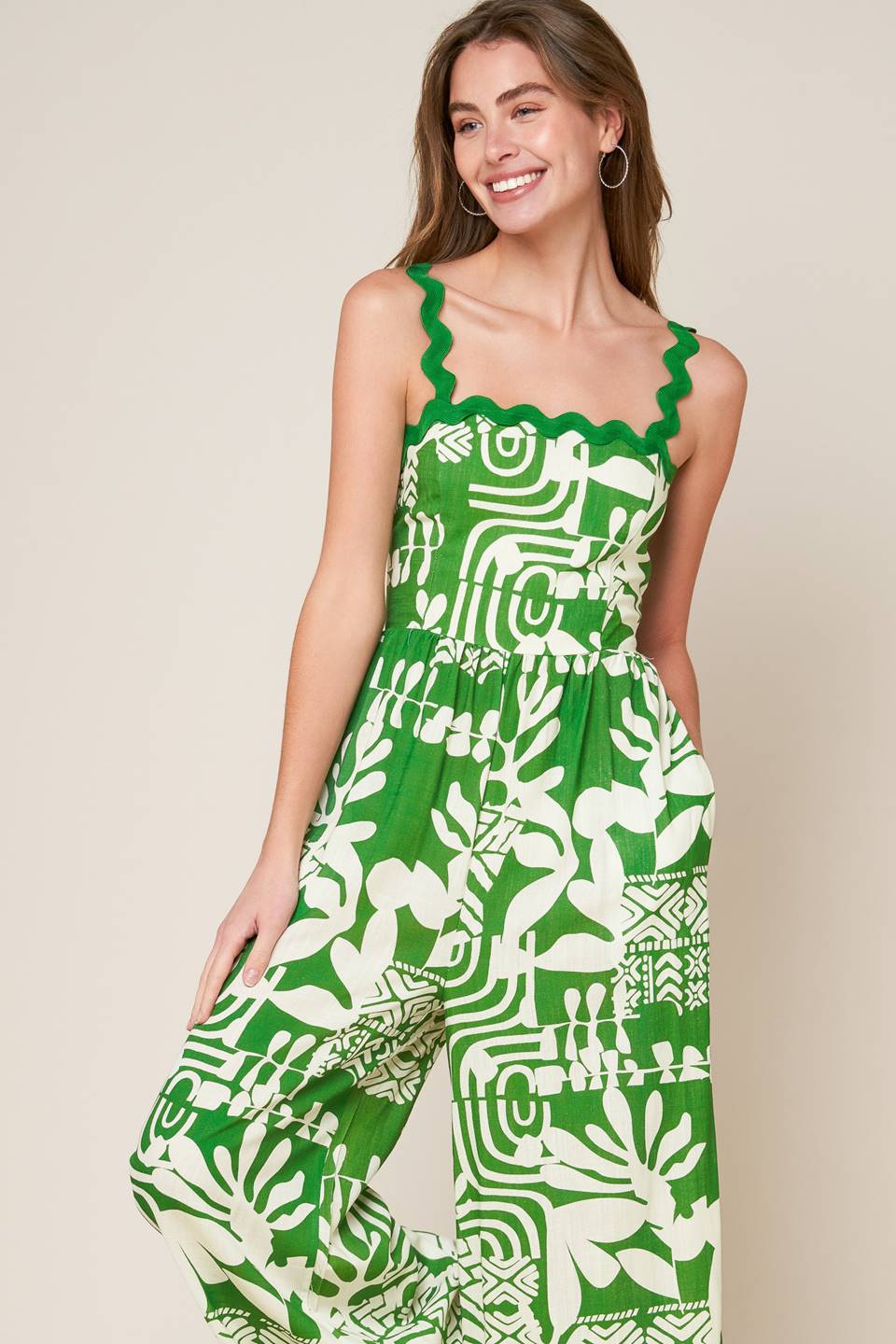 A printed woven jumpsuit featuring straight neckline with ric rac ribbon straps, wide leg and smocked back bodice