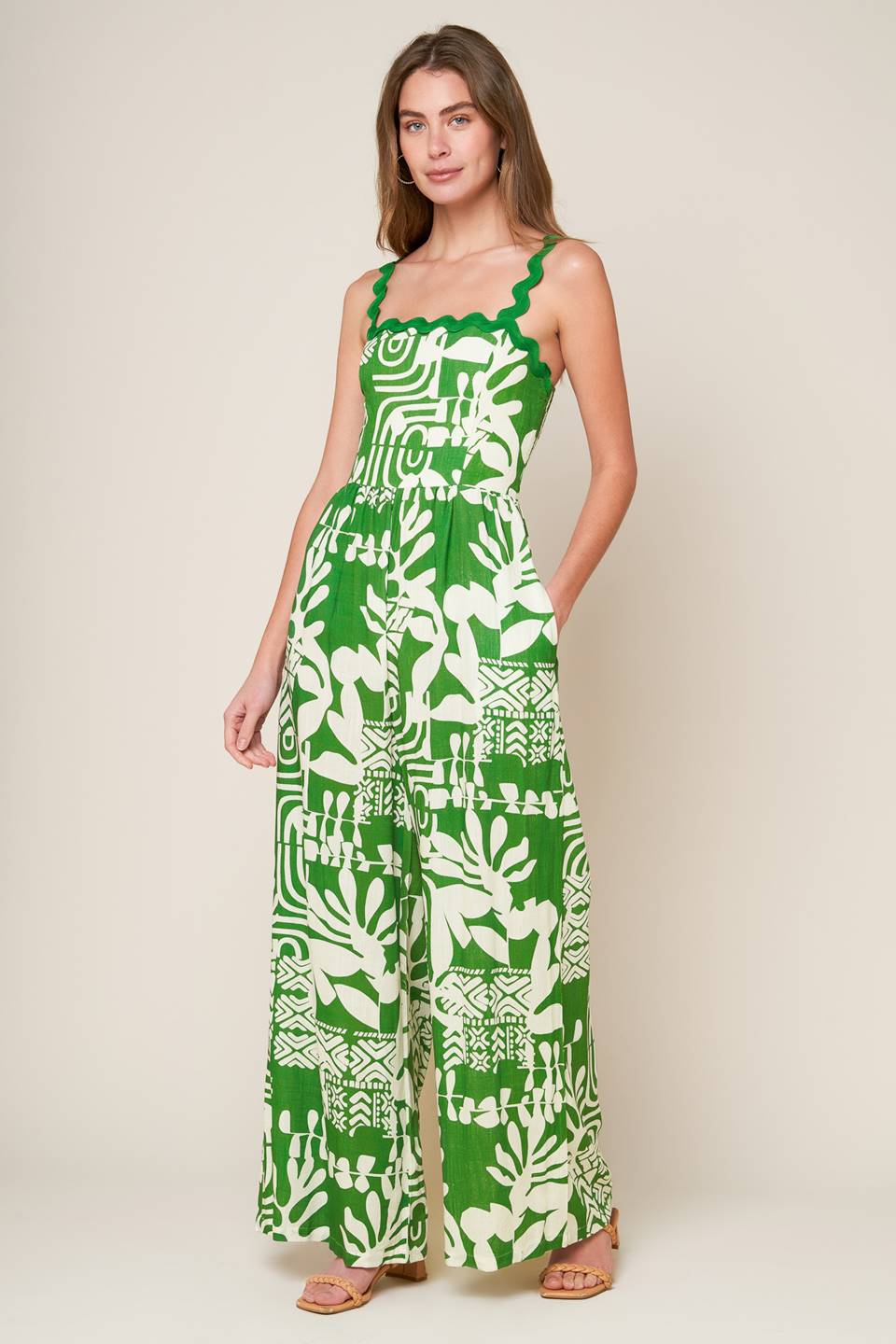 A printed woven jumpsuit featuring straight neckline with ric rac ribbon straps, wide leg and smocked back bodice