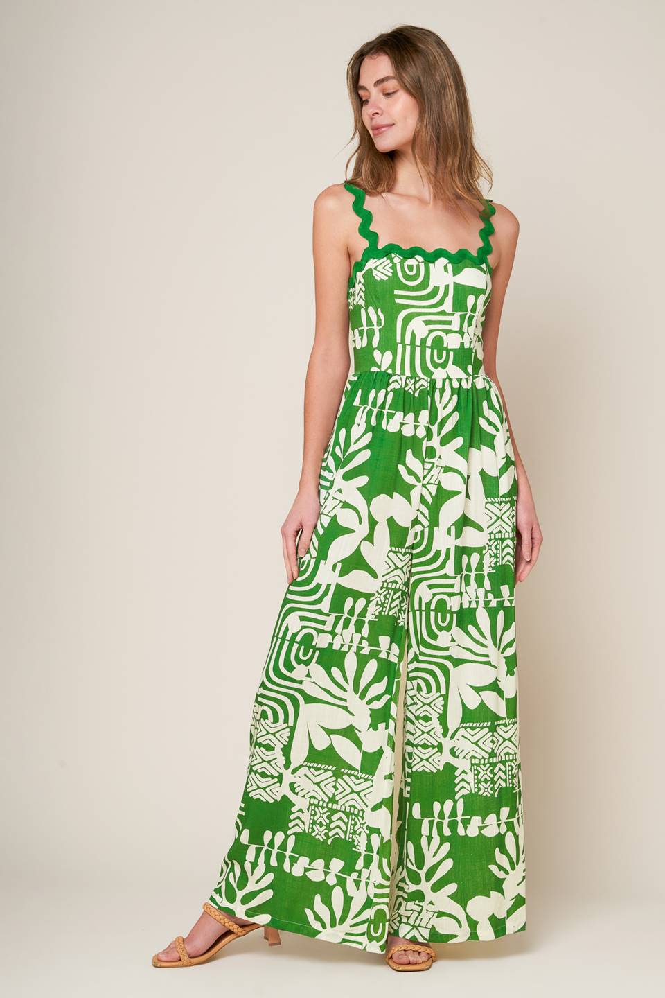 A printed woven jumpsuit featuring straight neckline with ric rac ribbon straps, wide leg and smocked back bodice