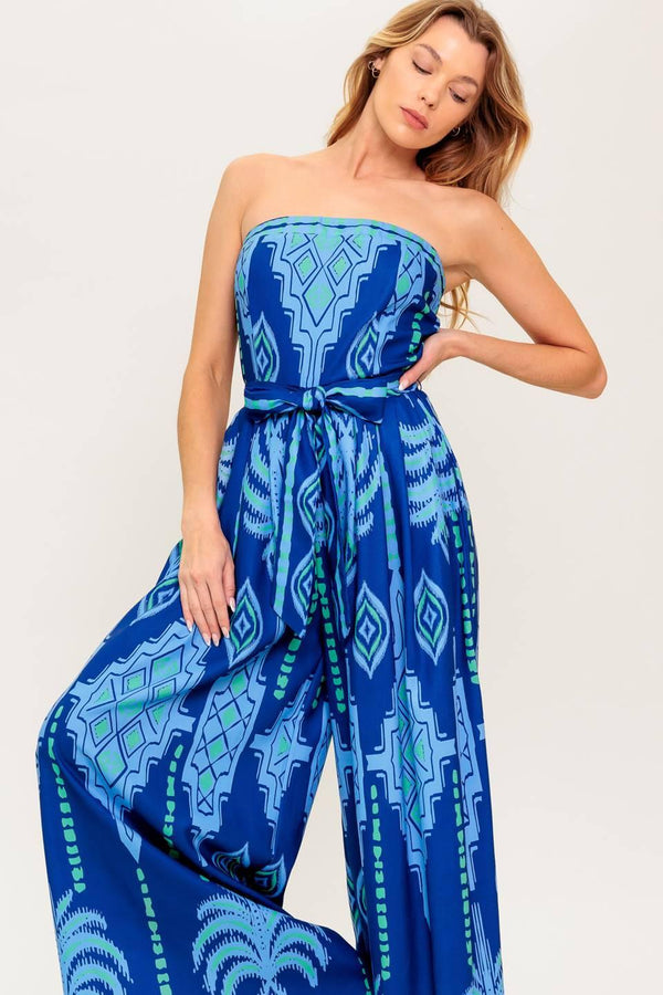 A printed woven jumpsuit featuring strapless, self sash tie, wide leg and back zipper closure
