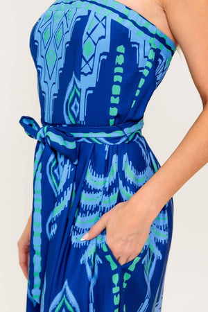 A printed woven jumpsuit featuring strapless, self sash tie, wide leg and back zipper closure