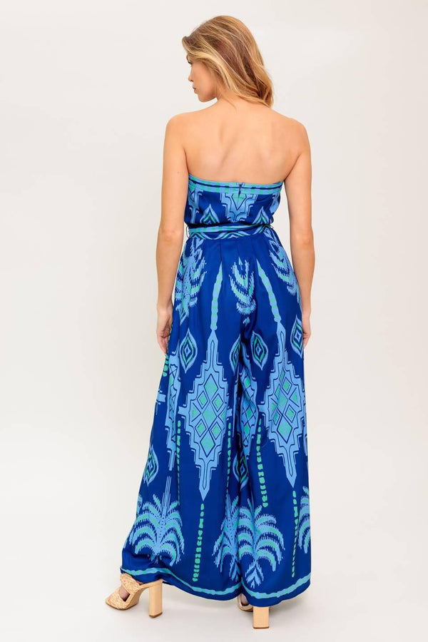A printed woven jumpsuit featuring strapless, self sash tie, wide leg and back zipper closure
