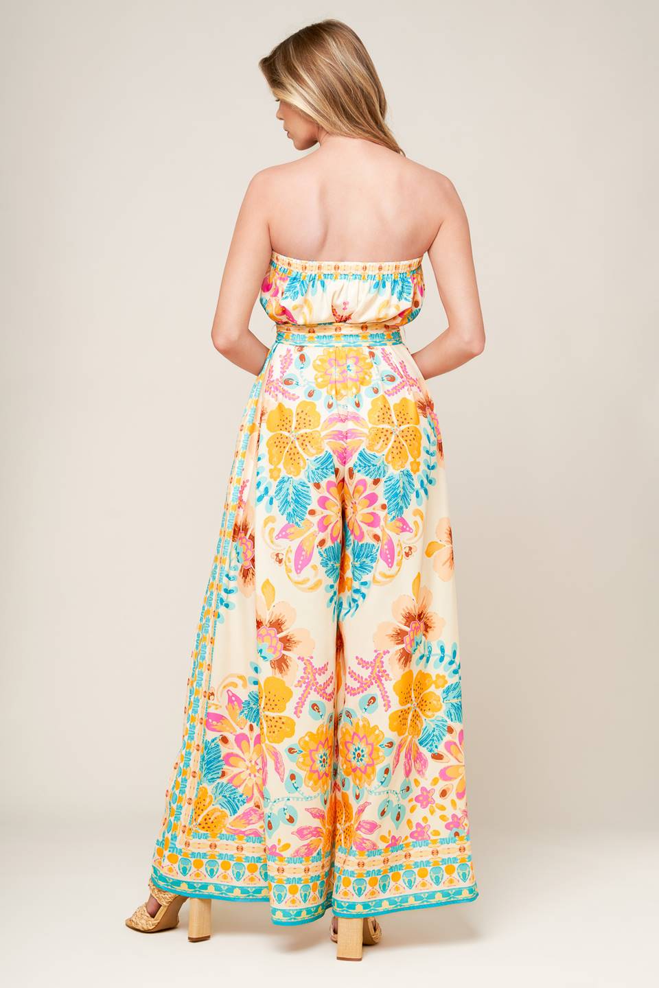 A printed woven jumpsuit featuring strapless, self sash belt and wide leg.