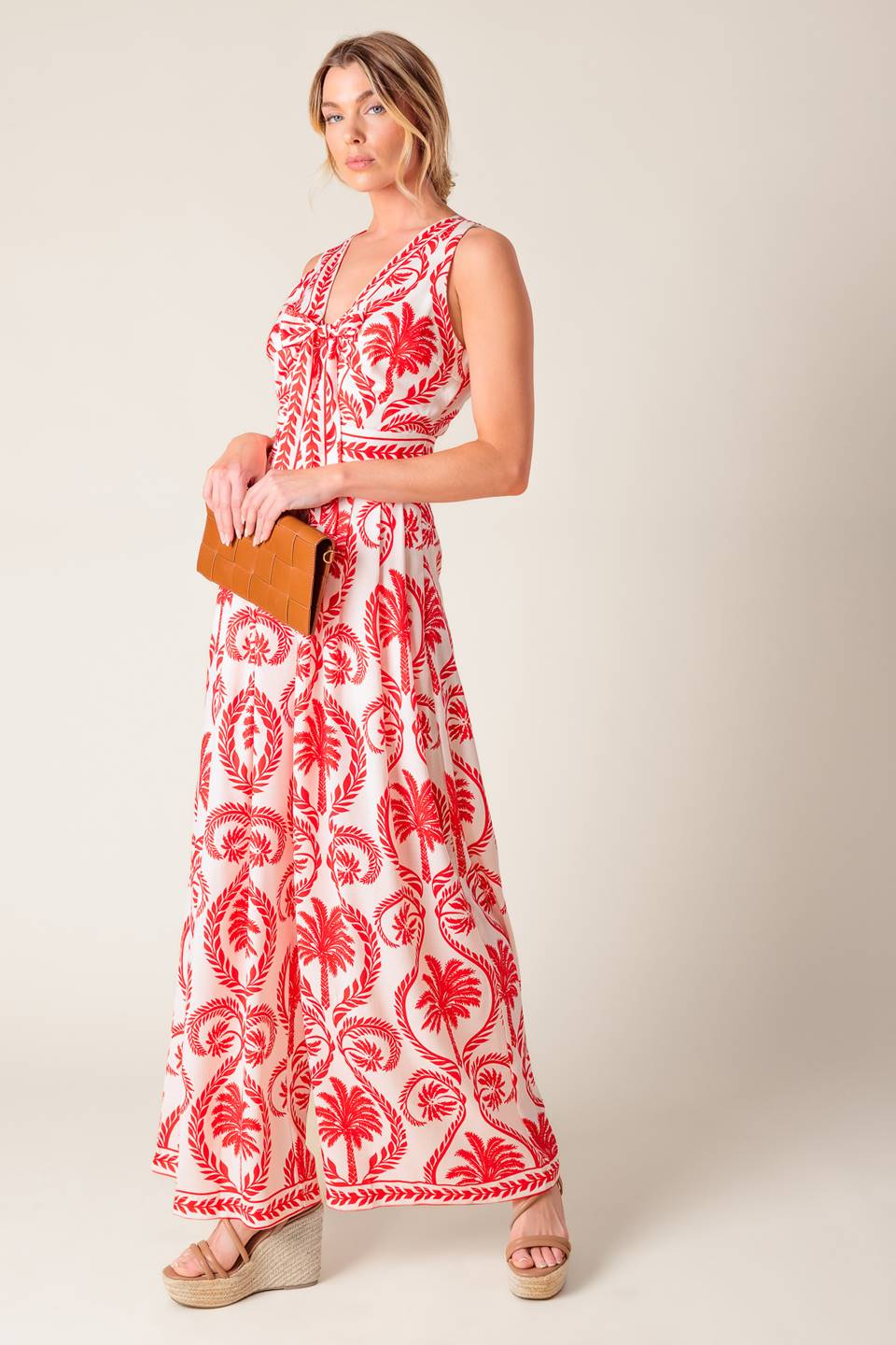 A white and red printed woven jumpsuit featuring V neckline with front tie, sleeveless, wide leg and back zipper closure.