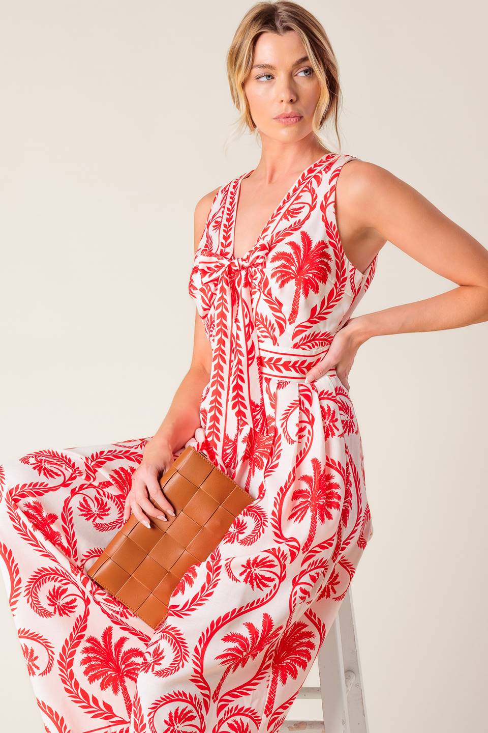 A white and red printed woven jumpsuit featuring V neckline with front tie, sleeveless, wide leg and back zipper closure.