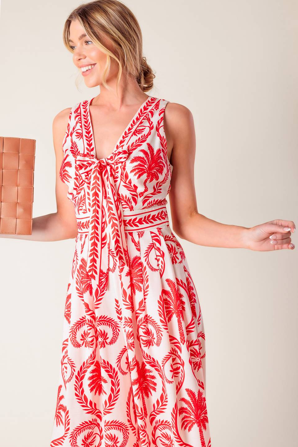 A white and red printed woven jumpsuit featuring V neckline with front tie, sleeveless, wide leg and back zipper closure.