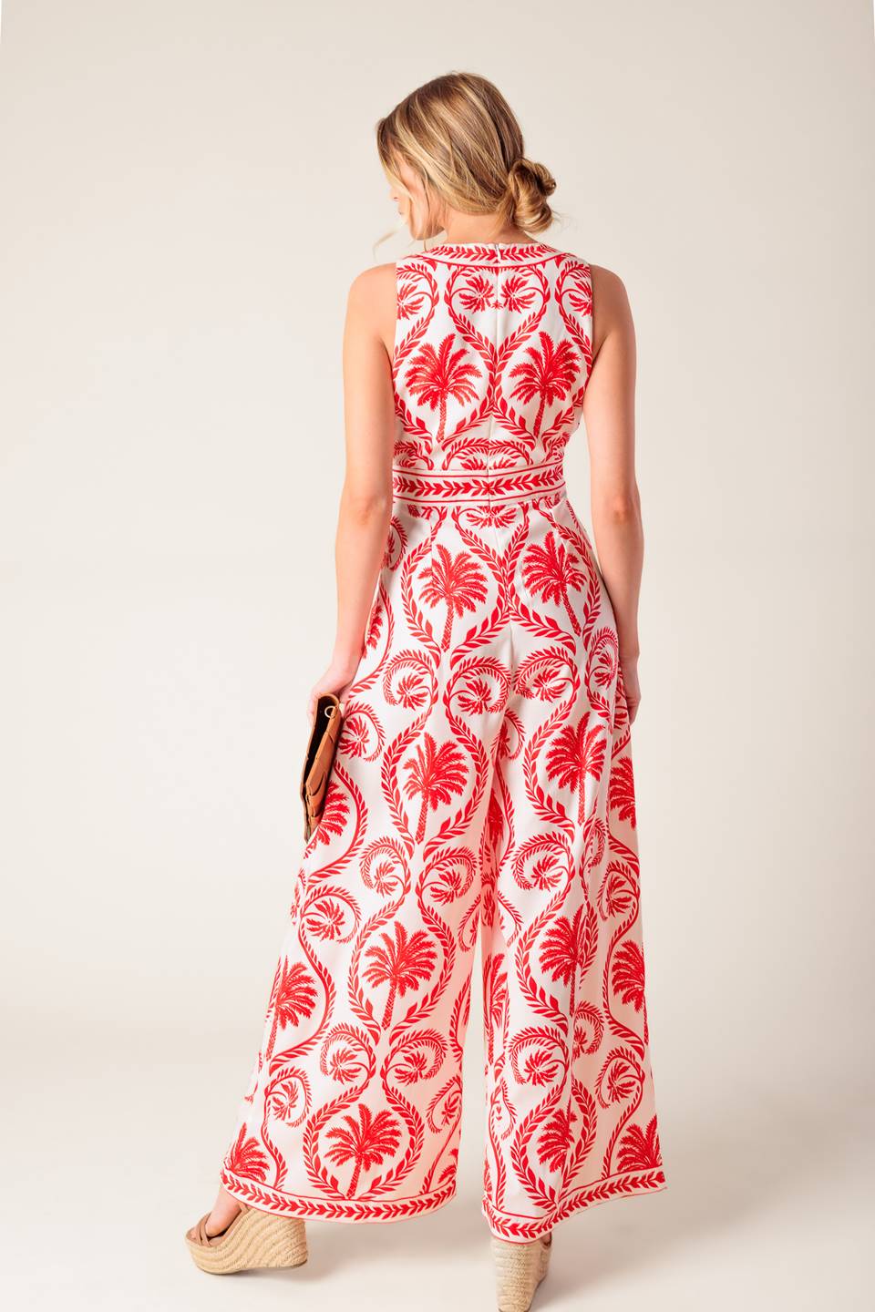 A white and red printed woven jumpsuit featuring V neckline with front tie, sleeveless, wide leg and back zipper closure.