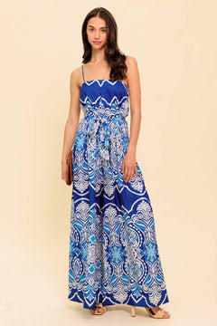 A printed woven jumpsuit featuring straight neckline, skinny straps, self sash belt and wide leg