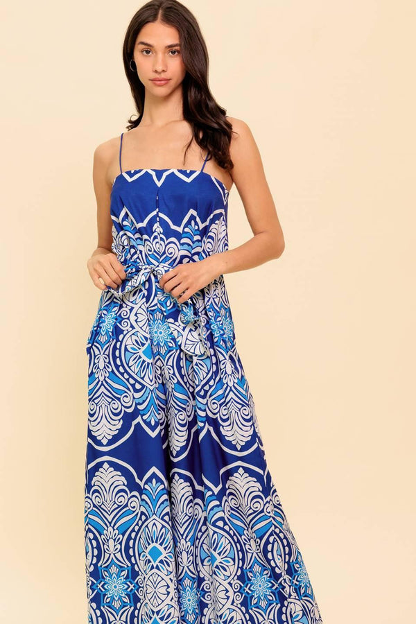 A printed woven jumpsuit featuring straight neckline, skinny straps, self sash belt and wide leg