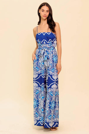 A printed woven jumpsuit featuring straight neckline, skinny straps, self sash belt and wide leg