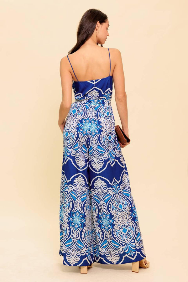 A printed woven jumpsuit featuring straight neckline, skinny straps, self sash belt and wide leg
