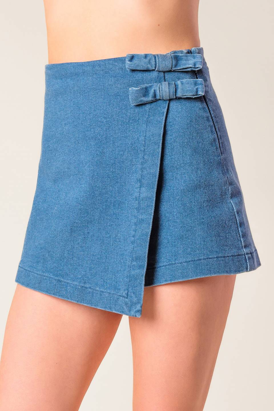 A washed denim mini skort with bow detail and side zipper closure.