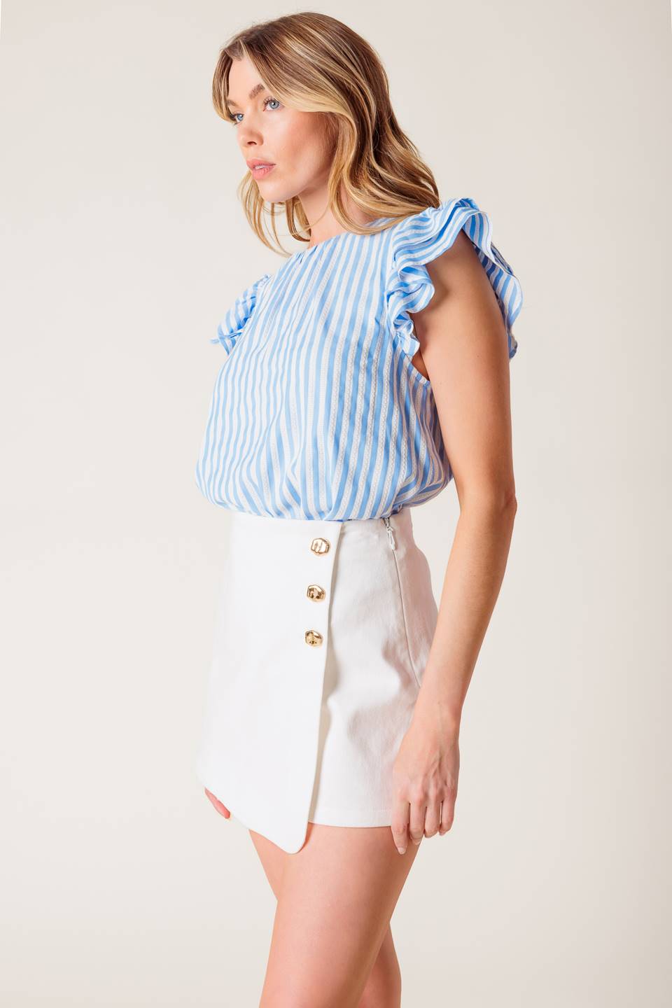 A solid white woven mini skort featuring front button detail and side zipper closure.