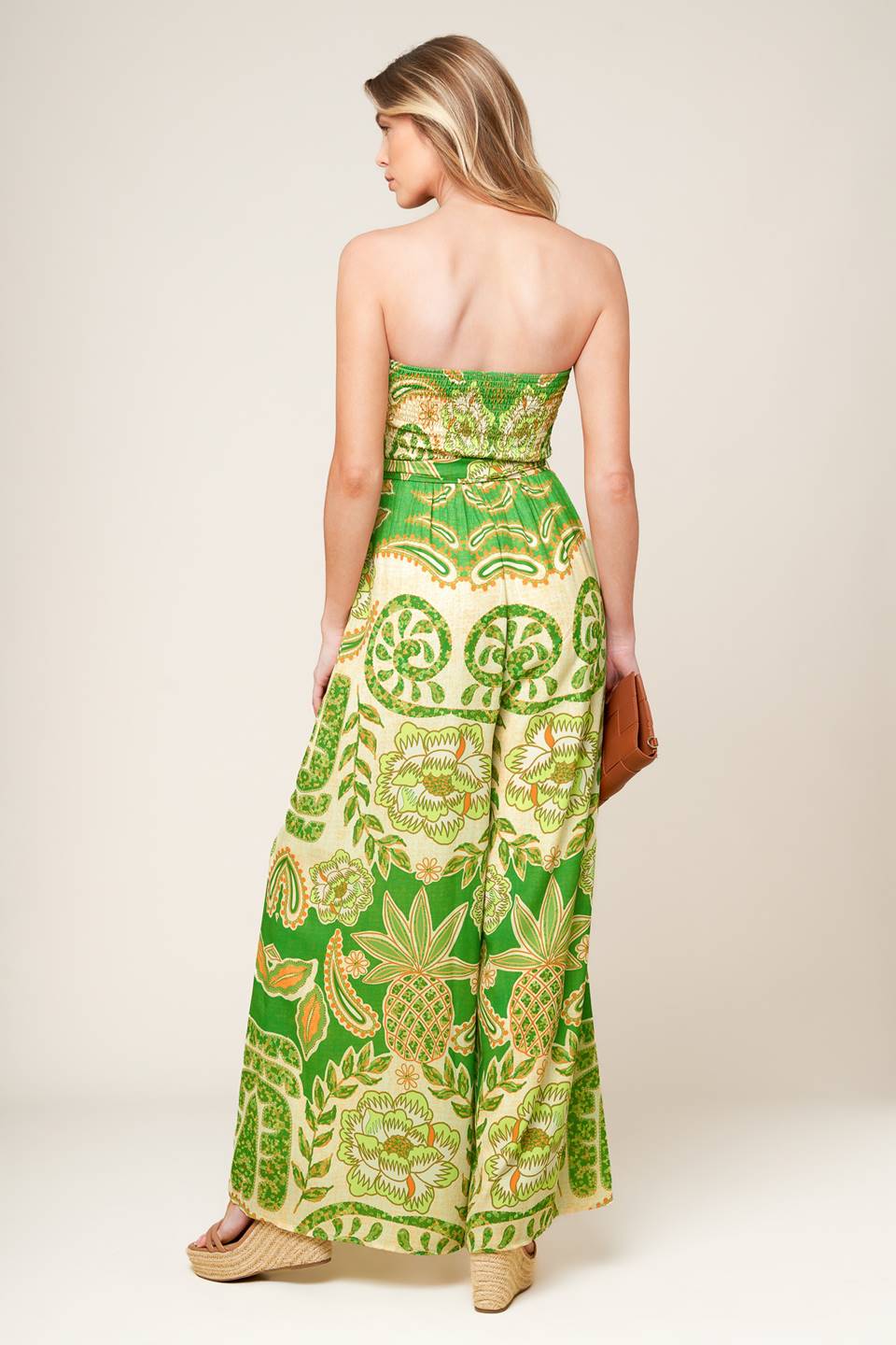 A printed woven jumpsuit featuring strapless, smocked bodice, self sash tie and wide leg