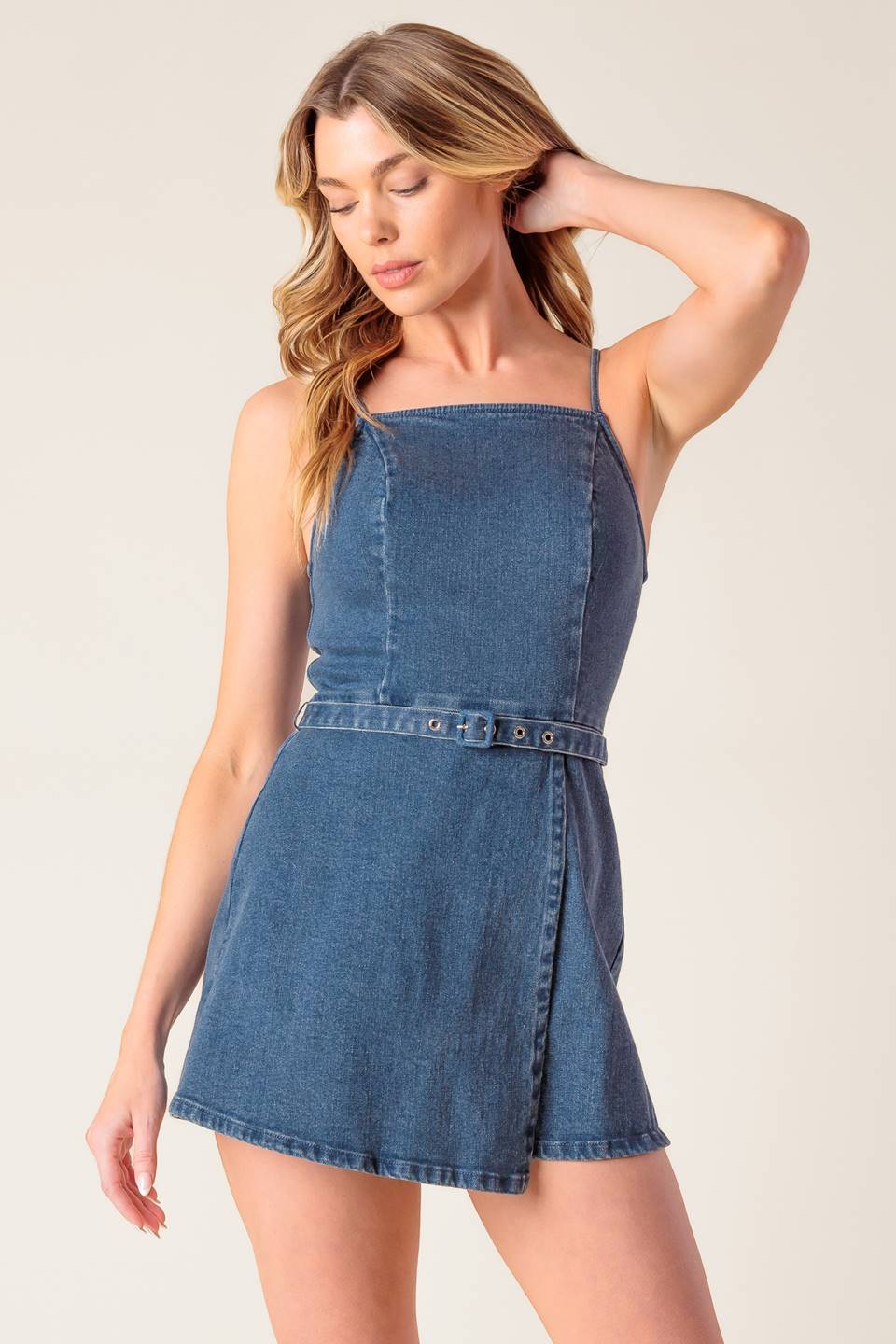 A washed denim skort romper featuring straight neckline, straps, self belt and back zipper closure.