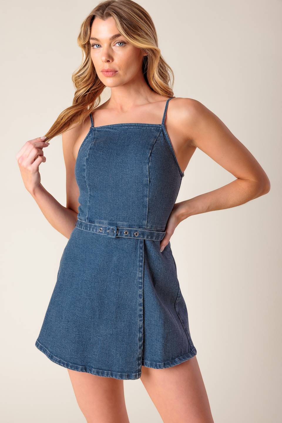 A washed denim skort romper featuring straight neckline, straps, self belt and back zipper closure.