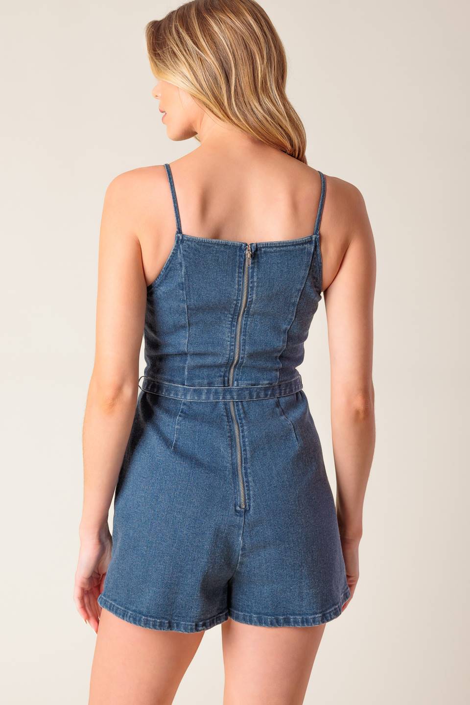 A washed denim skort romper featuring straight neckline, straps, self belt and back zipper closure.