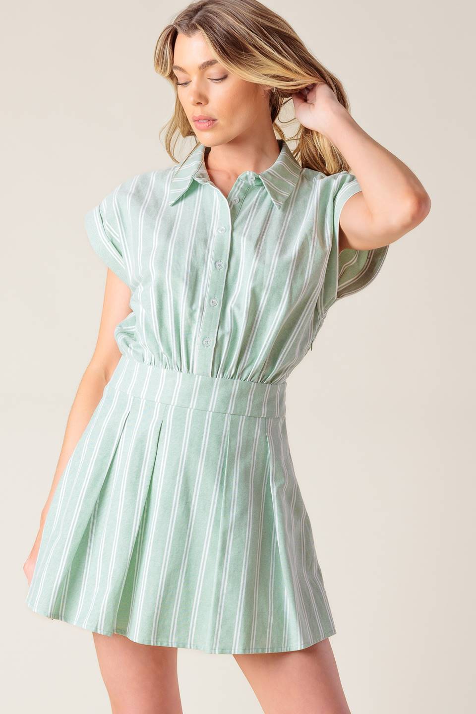 A striped woven romper featuring collar, button down, short cuffed sleeve, inverted pleat skort and side zipper closure.