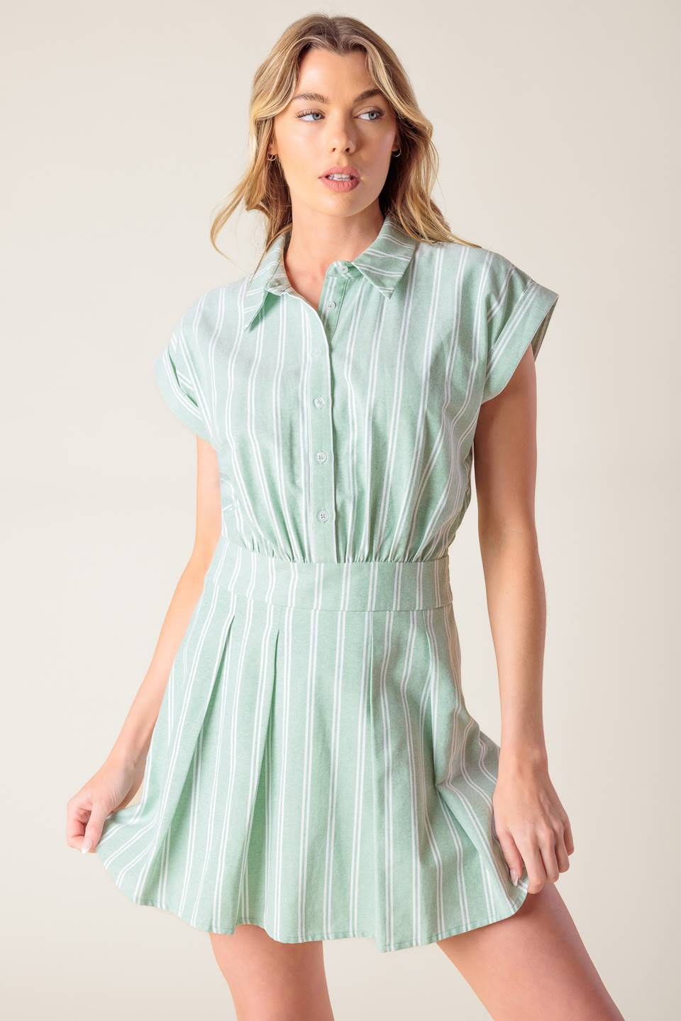 A striped woven romper featuring collar, button down, short cuffed sleeve, inverted pleat skort and side zipper closure.