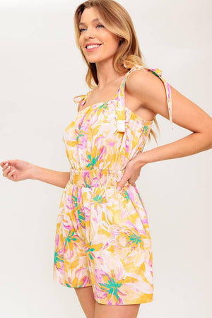 A printed woven romper featuring straight neckline, shoulder tie and smocked waistband